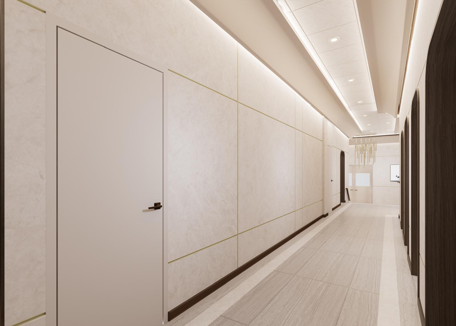 Perspective down the stone-clad corridor toward the chandelier and beis medrash entry doors