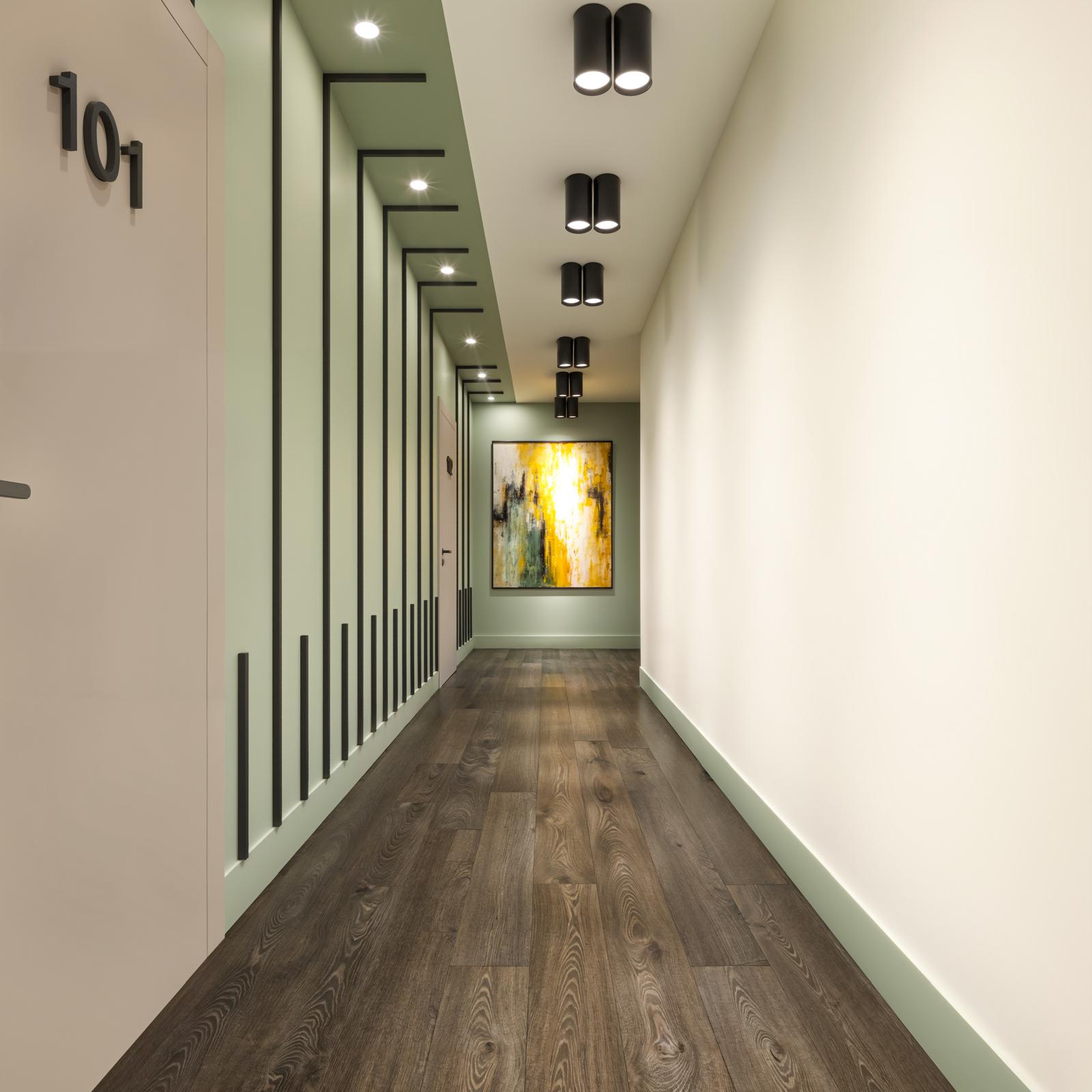 Residential corridor with sage batten accent wall, blush unit door 101 and dark oak flooring