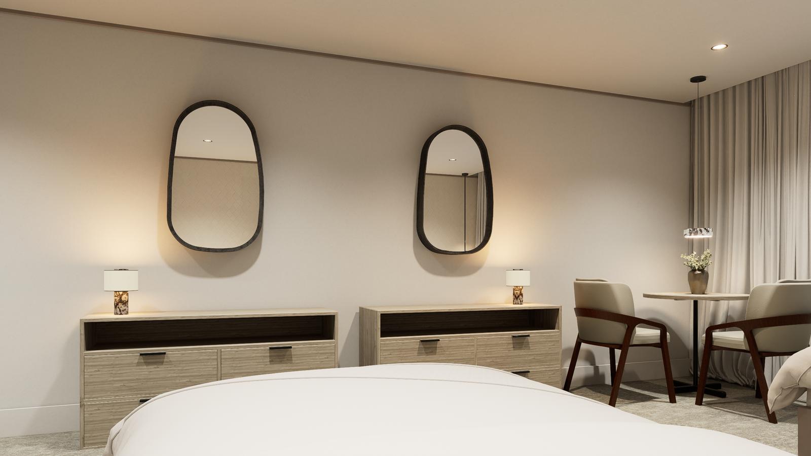 Paired oval mirrors above oak dressers with table lamps and a window seating nook beyond