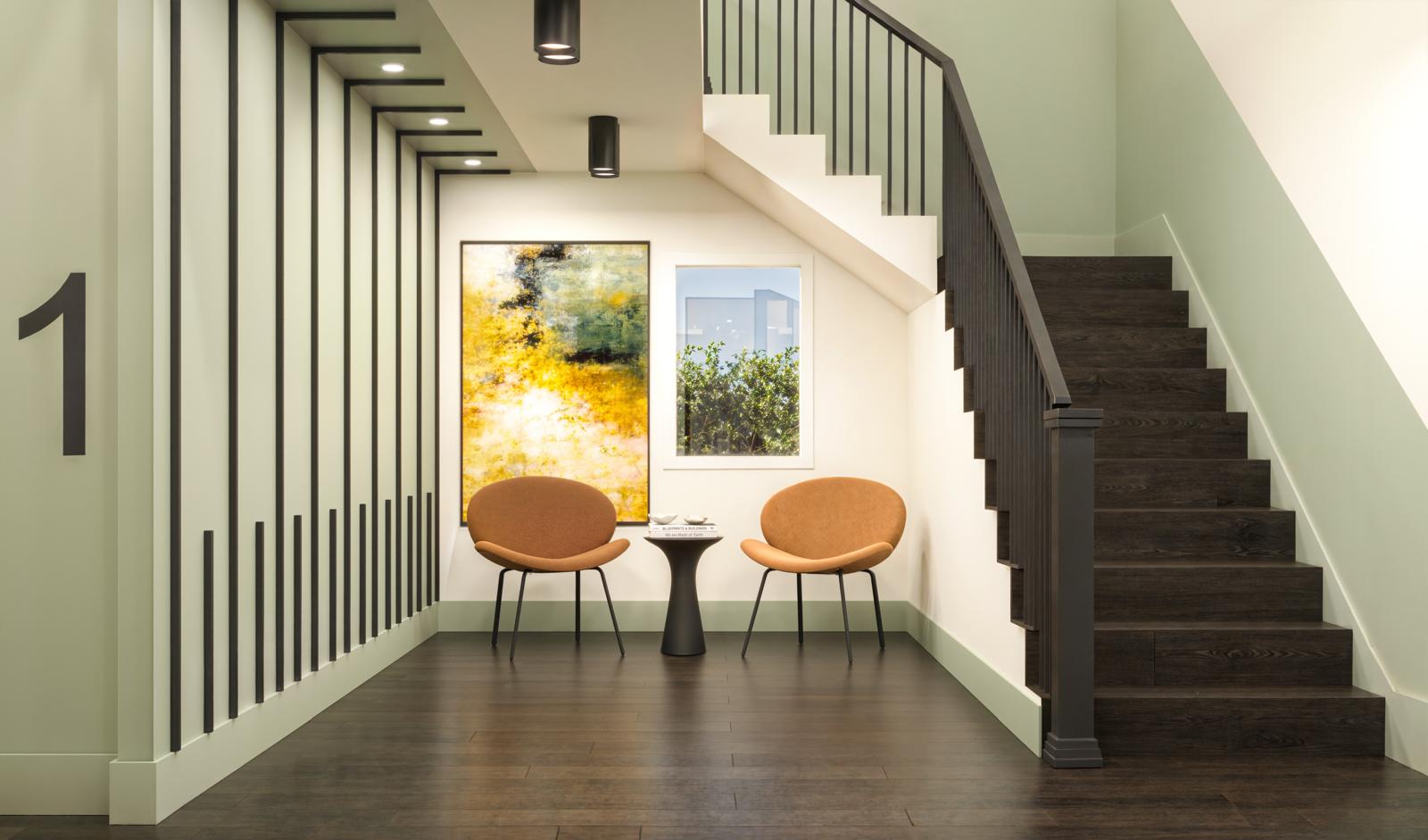 Stair lounge with terracotta lounge chairs, abstract artwork and dark oak stair